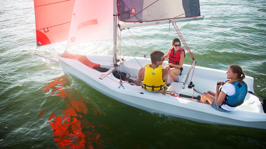 Laser Bahia sailing dinghy sailing with three young people in buoyancy aids