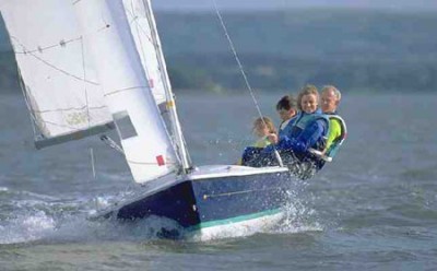 group of 4 people on a blue sailing dinghy learning to sail with Mylor Sailing School