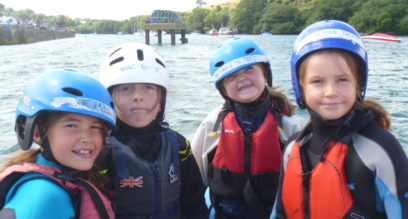 Four children with helmets on ready for sailing at Mylor Sailing School in Cornwall