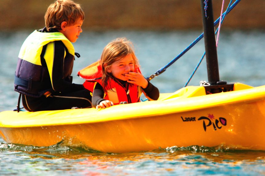 Two children sailing in a small yellow boat in Cornwall