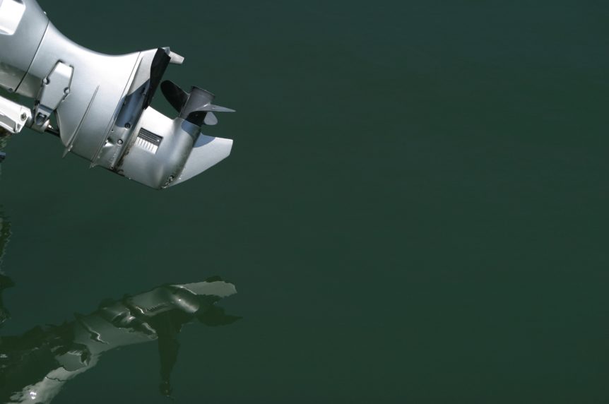 lower leg and propellor of outboard engine with reflection on calm water at Mylor Sailing School Powerboating near Falmouth, Cornwall