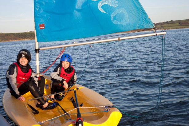 Two children sailing a small yellow boat in Falmouth