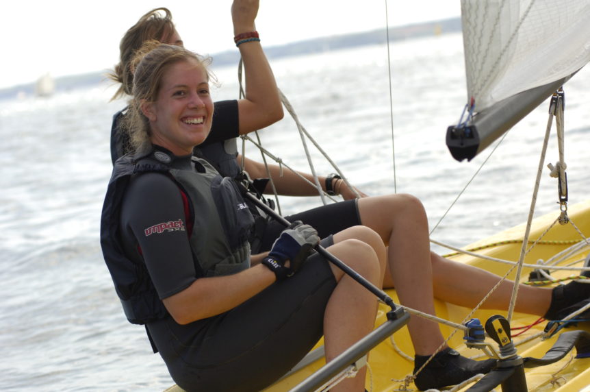 Two ladies sailing a small yellow sailing dinghy at Mylor sailing school near Falmouth