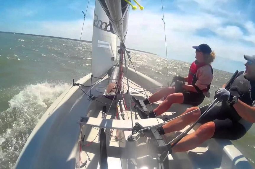 Two adults hiking out in a sailing dinghy on a sunny day at Mylor Sailing School in ornwall