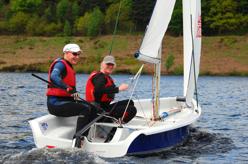 Two men sailing a Laser 2000 dinghy having fun at Mylor Sailing School Falmouth in Cornwall