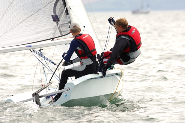 Two teenagers sailing a dinghy and trapezing at Mylor Sailing School in Falmouth Cornwall