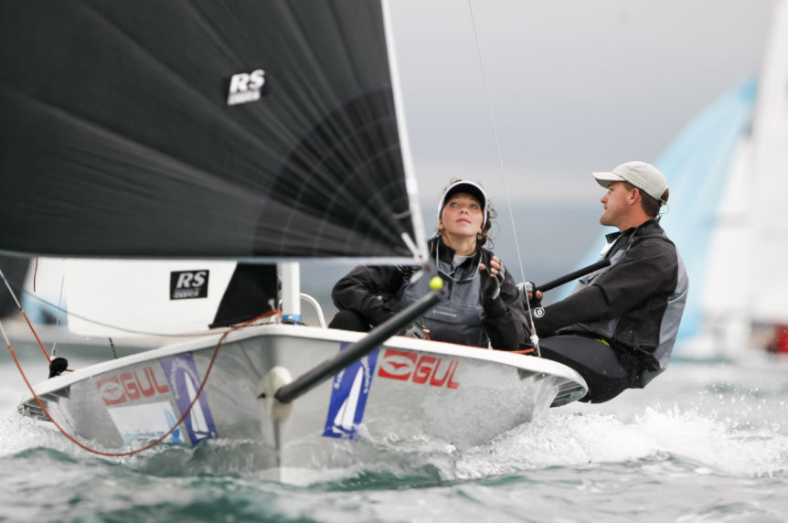 Two people sailing with a black spinnaker on a performance dinghy