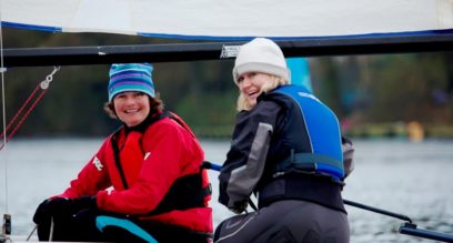 Two ladies smiling sailing a small dinghy at Mylor Sailing School near Falmouth Cornwall