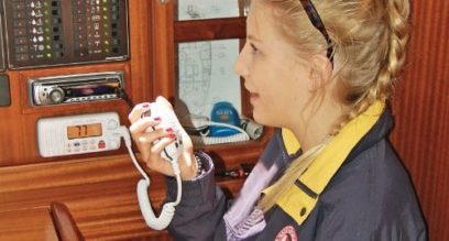 lady operating a fixed VHF radio down below deck on a yacht at mylor sailing school near Falmouth, Cornwall