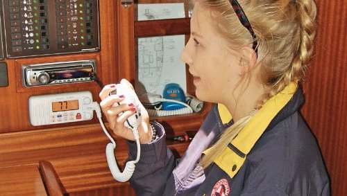 lady operating a fixed VHF radio down below deck on a yacht at mylor sailing school near Falmouth, Cornwall