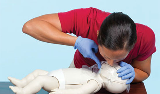 Lady demonstrating mouth to mouth resuscitation on a child dummy