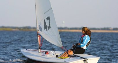 Teenage girl sailing a Laser 4.7 on a sunny day at Mylor Sailing School near Falmouth, Cornwall