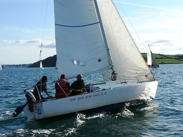 Three adults sailing on a 24 foot keelboat at Mylor Sailing School