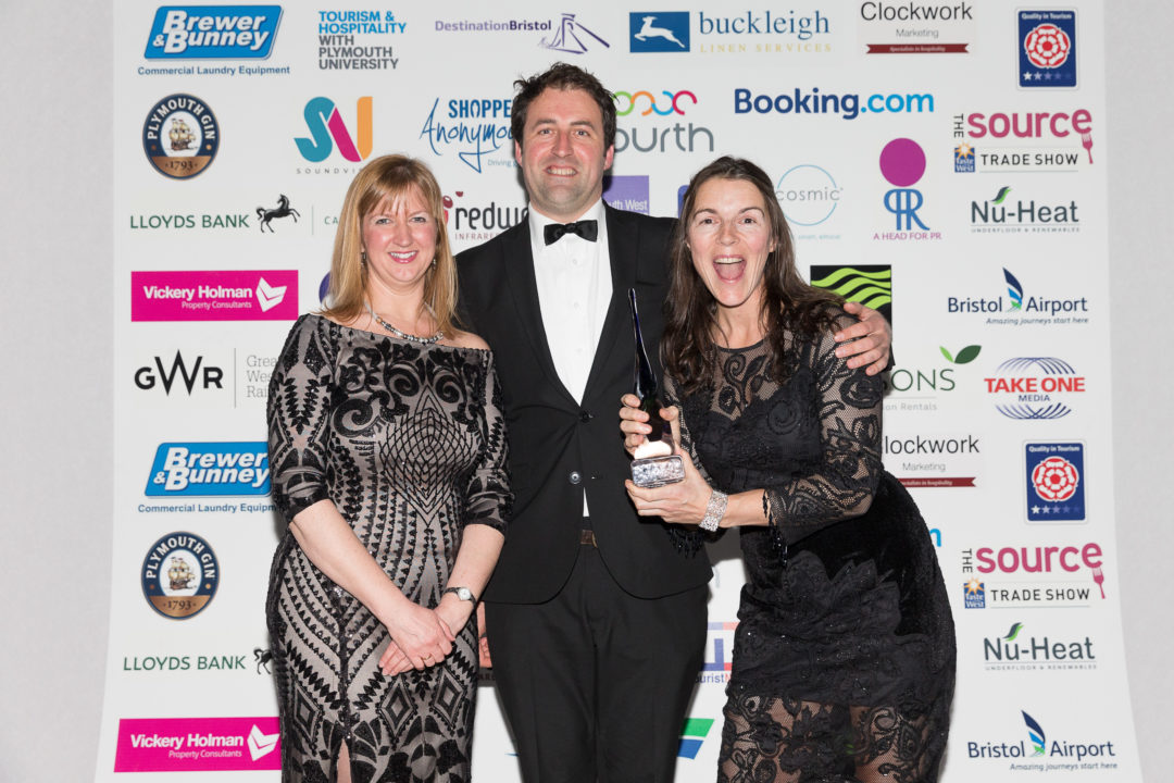 Three people in black tie holding a tourism award for Mylor Sailing School near Falmouth