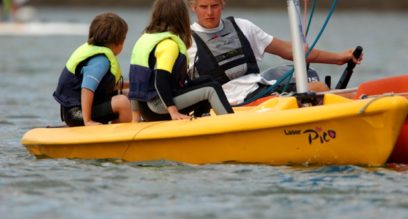 Sailing instructor teaching 2 children in a dinghy at Mylor Sailing School Falmouth Cornwall