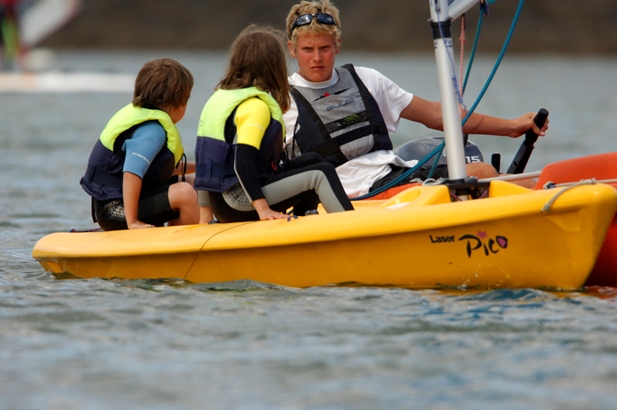 Sailing instructor teaching 2 children in a dinghy at Mylor Sailing School Falmouth Cornwall