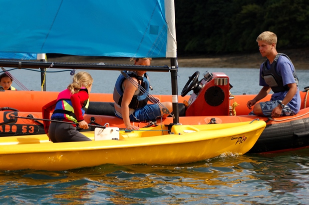 2 instructors teaching a child to sail from a rescue boat at Mylor Sailing School in Falmouth Cornwall