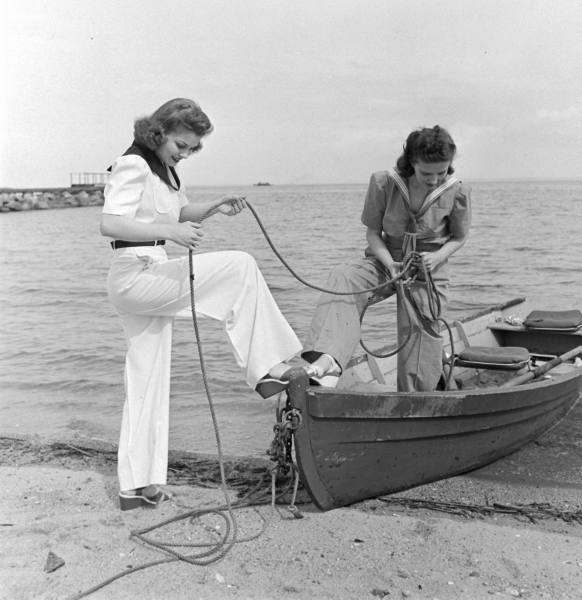 Two ladies in a black and white photo holding a rope on a small rowing boat at Mylor Sailing School Falmouth Cornwall