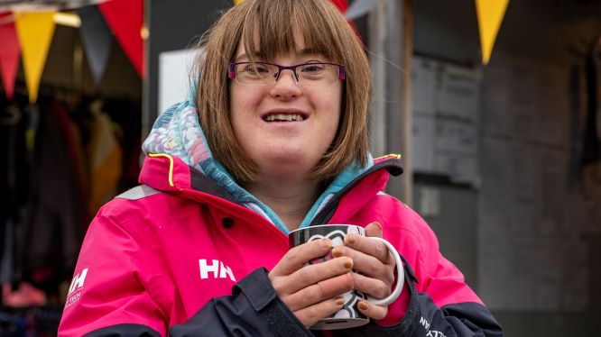 Girl with downs syndrome having a cup of tea and smiling at Mylor Sailing School Falmouth Cornwall