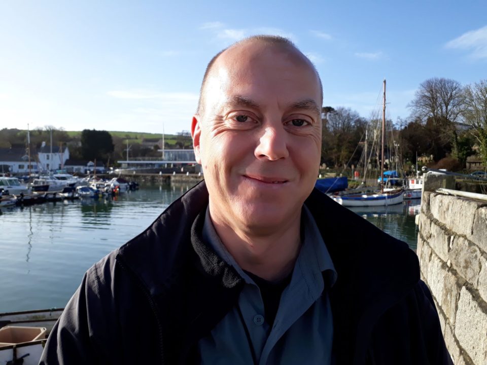 Man stood by the water smiling Simon Chapman a trainer at Mylor Sailing and Powerboat School Falmouth Cornwall