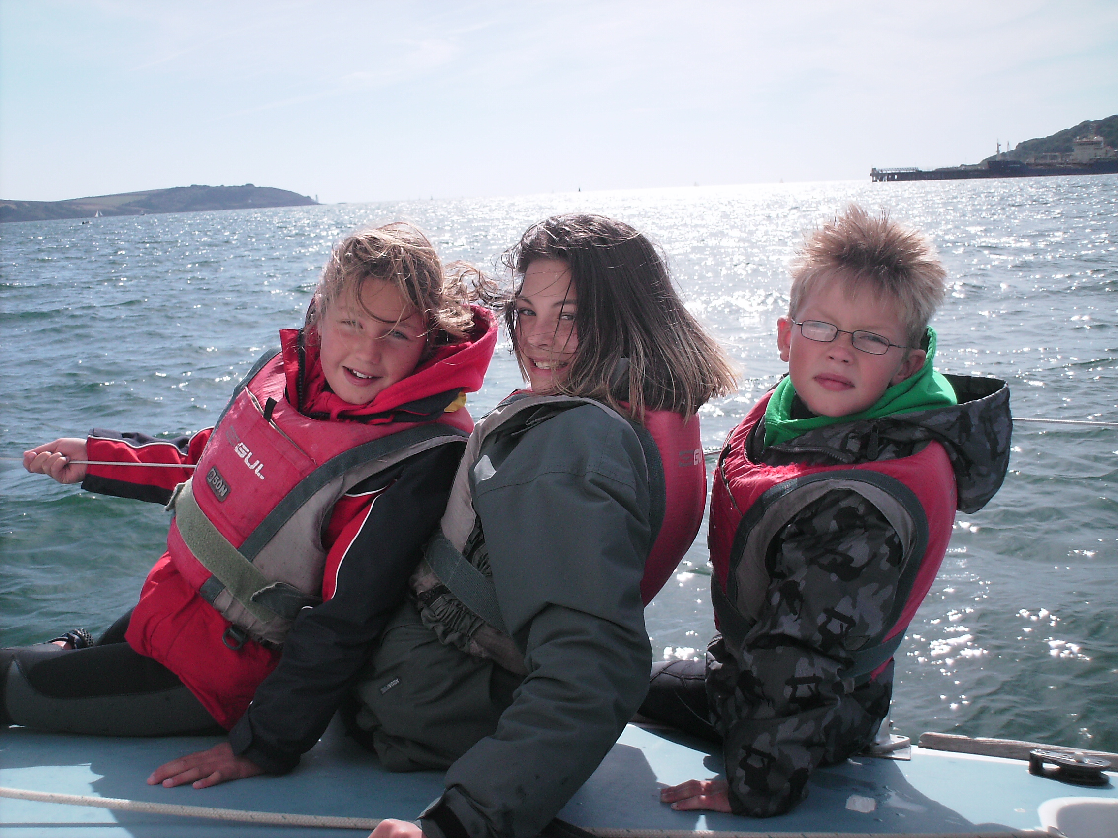 Three children sailing on a keelboat in sunny Falmouth at Mylor Sailing and Powerboat School Falmouth Cornwall