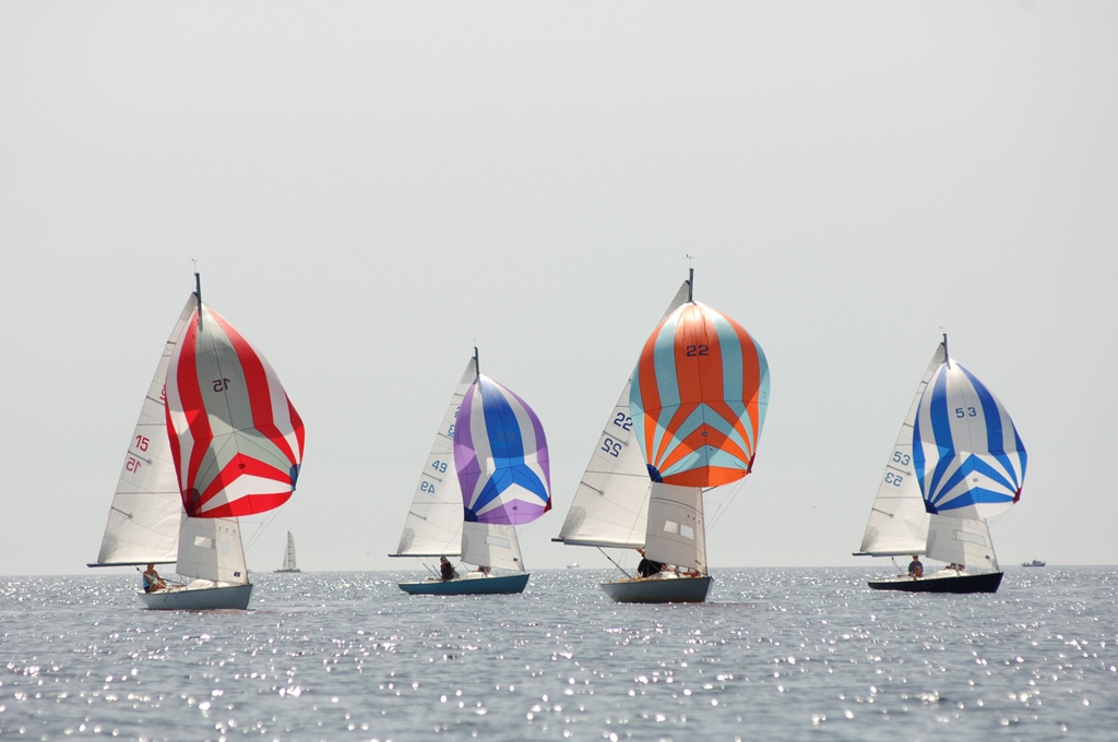 4 sailing boats with brightly coloured spinnaker sails flying