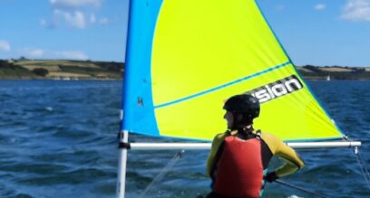 sailor in dinghy with helmet on Mylor Sailing School Falmouth Cornwall