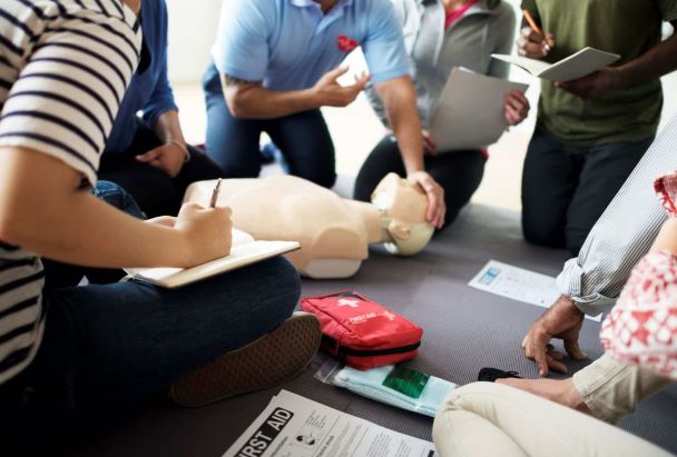 adults sat on the floor taking training for first aid